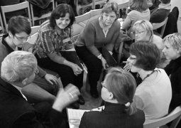 Eine Gruppe von Meschen sitz im Kreis und diskuttiert angeregt